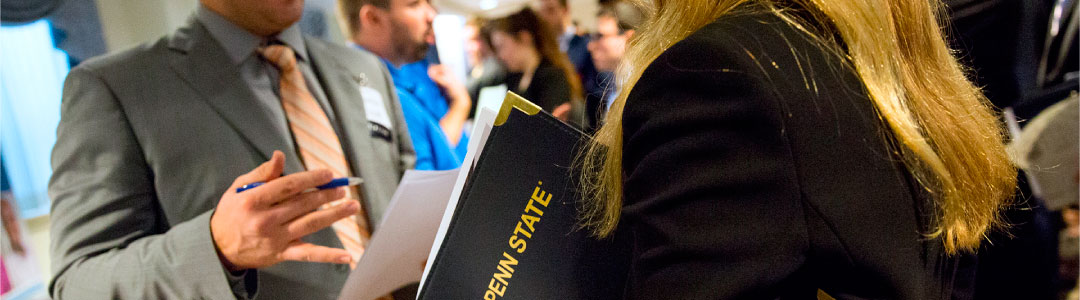 Photo of student holding a Penn State folder and talking to a recruiter